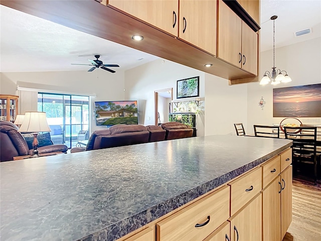 kitchen featuring light brown cabinetry, open floor plan, visible vents, and lofted ceiling