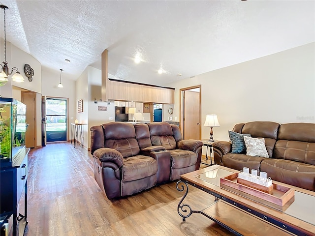 living room with a textured ceiling, light wood-type flooring, and lofted ceiling