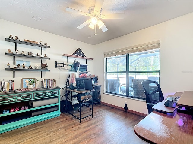 office featuring wood finished floors, a ceiling fan, baseboards, and a textured ceiling