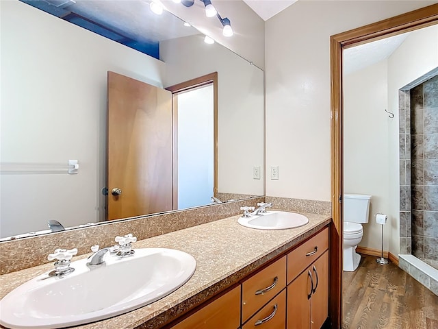 bathroom with a sink, toilet, wood finished floors, and double vanity