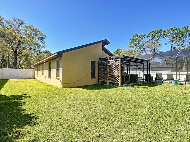 exterior space featuring a lanai, a fenced backyard, a lawn, and stucco siding