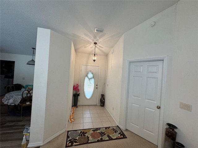 entryway with light tile patterned floors, baseboards, and visible vents