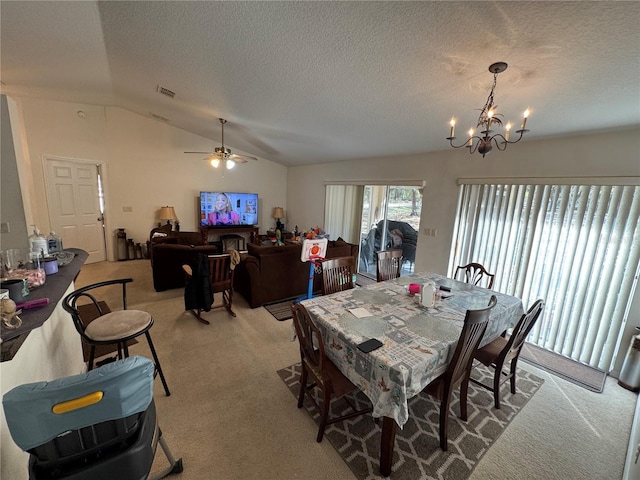 dining room with visible vents, carpet, vaulted ceiling, ceiling fan with notable chandelier, and a textured ceiling