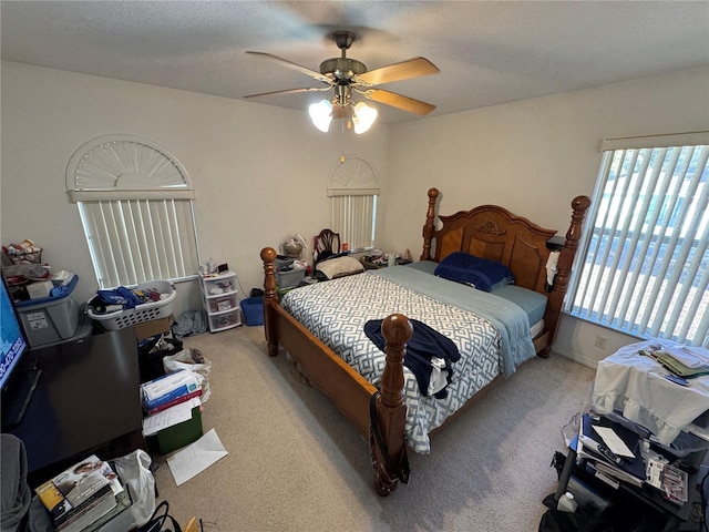 bedroom featuring light carpet, a textured ceiling, and a ceiling fan