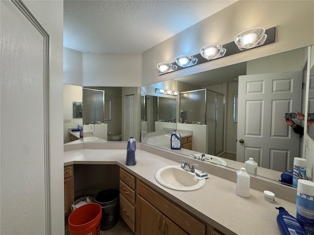 full bath featuring a textured ceiling, a stall shower, and vanity