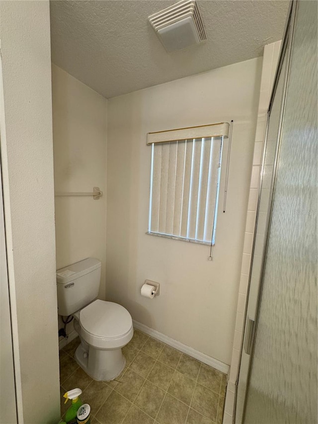 bathroom featuring visible vents, toilet, a textured ceiling, a shower stall, and baseboards