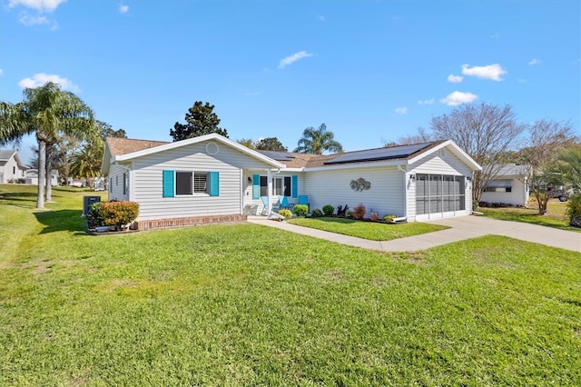 ranch-style house featuring solar panels, an attached garage, concrete driveway, and a front lawn