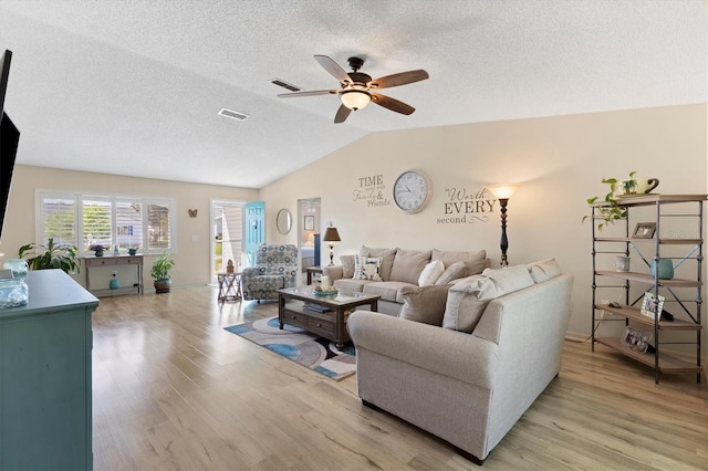 living area with visible vents, light wood-style floors, a ceiling fan, and vaulted ceiling