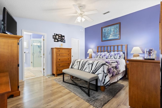 bedroom featuring a ceiling fan, visible vents, lofted ceiling, light wood-style flooring, and connected bathroom