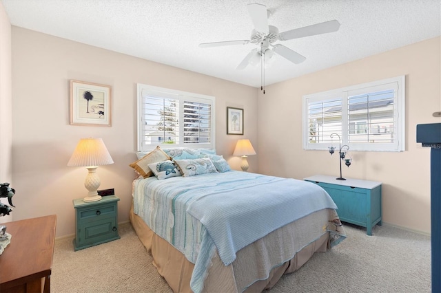 bedroom featuring light colored carpet, a textured ceiling, baseboards, and a ceiling fan