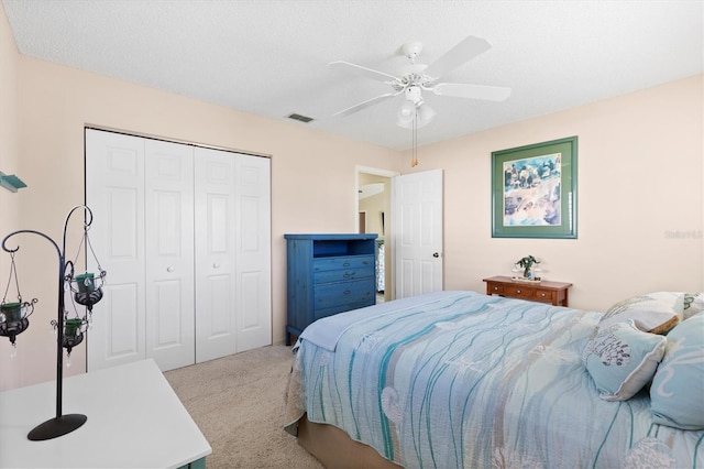 carpeted bedroom with visible vents, a closet, and a ceiling fan