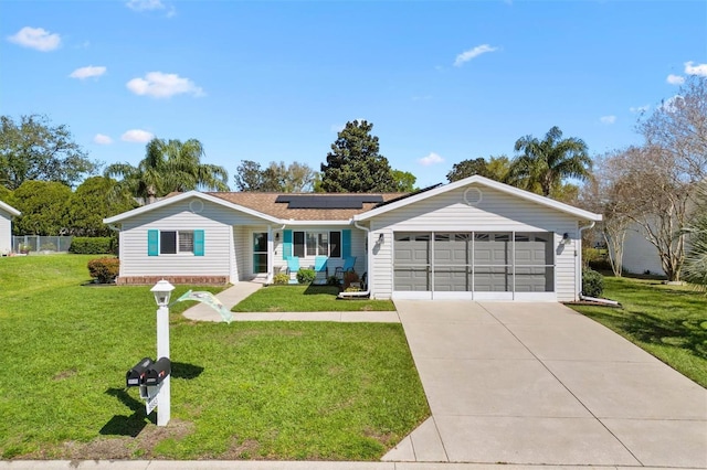 ranch-style house with roof mounted solar panels, driveway, an attached garage, and a front yard