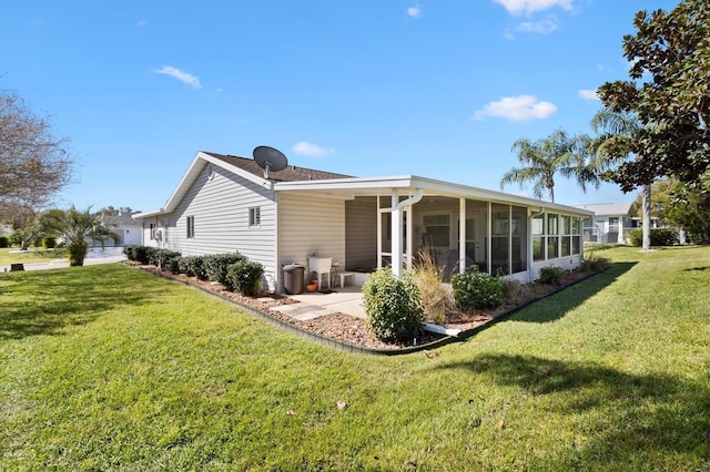 back of property featuring a yard, a garage, and a sunroom