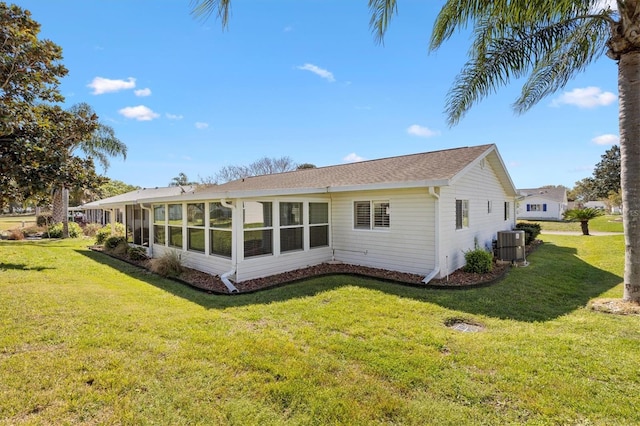 rear view of house with central air condition unit, a lawn, and a sunroom