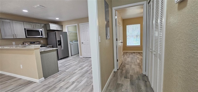 5975 NW 6th Pl, Ocala, FL 34482 - kitchen with light countertops, independent washer and dryer, visible vents, light wood-style flooring, and appliances with stainless steel finishes
