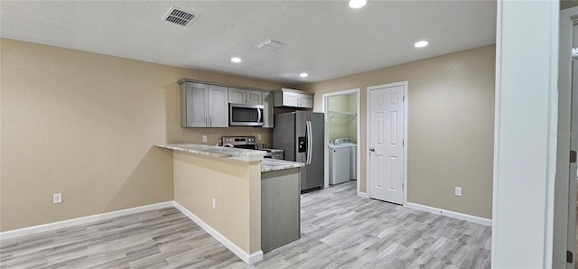 5975 NW 6th Pl, Ocala, FL 34482 - kitchen featuring washing machine and clothes dryer, stainless steel appliances, light wood-style flooring, and visible vents