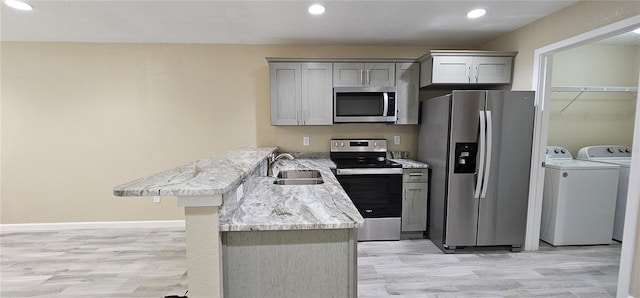 5975 NW 6th Pl, Ocala, FL 34482 - kitchen featuring gray cabinets, stainless steel appliances, a sink, a peninsula, and washing machine and dryer