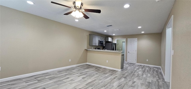 5975 NW 6th Pl, Ocala, FL 34482 - kitchen featuring light countertops, freestanding refrigerator, light wood-style flooring, stainless steel microwave, and baseboards