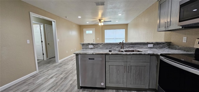 5975 NW 6th Pl, Ocala, FL 34482 - kitchen with light stone counters, a sink, appliances with stainless steel finishes, a peninsula, and gray cabinetry