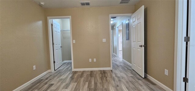 5975 NW 6th Pl, Ocala, FL 34482 - unfurnished bedroom with a walk in closet, baseboards, light wood-style floors, and visible vents