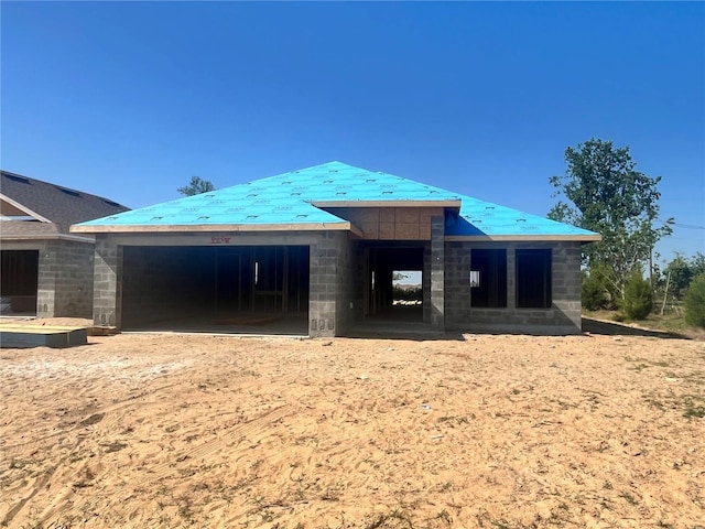 back of house featuring a garage, concrete block siding, and metal roof