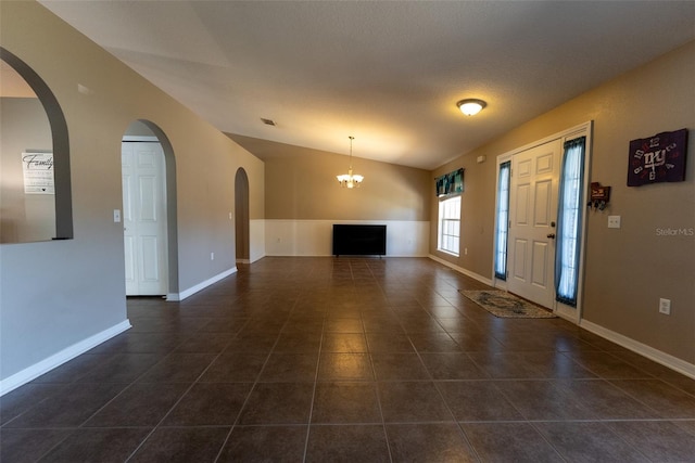 entrance foyer featuring a notable chandelier, baseboards, lofted ceiling, and dark tile patterned flooring