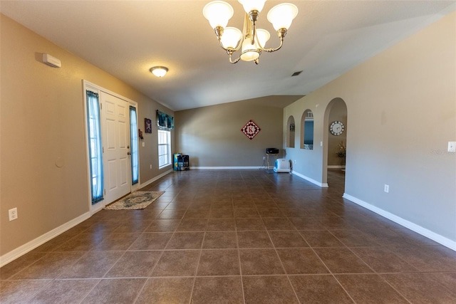 entrance foyer featuring visible vents, a notable chandelier, dark tile patterned floors, arched walkways, and baseboards