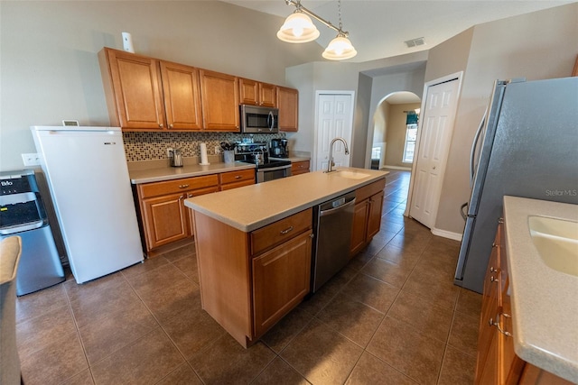 kitchen featuring visible vents, decorative backsplash, appliances with stainless steel finishes, arched walkways, and a sink