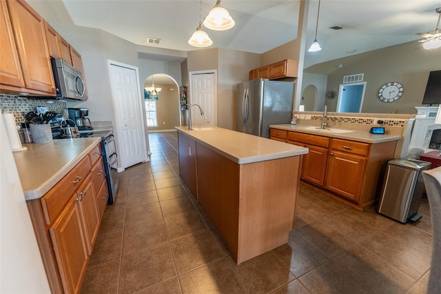 kitchen featuring visible vents, a kitchen island with sink, arched walkways, appliances with stainless steel finishes, and light countertops