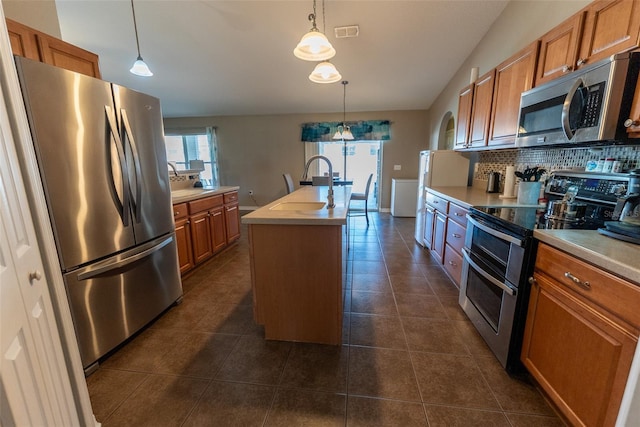 kitchen with visible vents, an island with sink, stainless steel appliances, light countertops, and backsplash