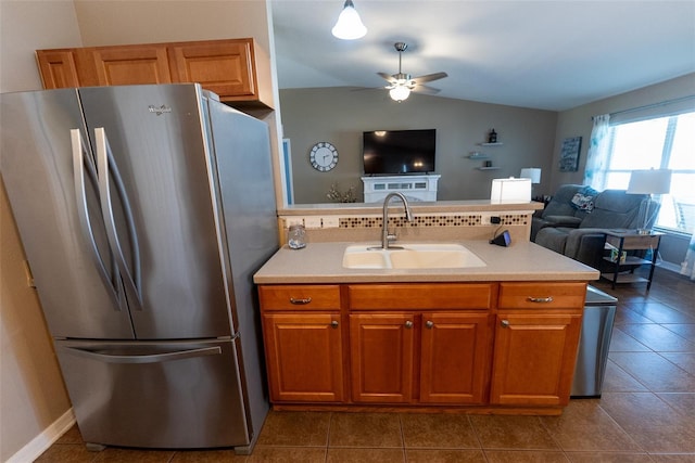 kitchen with brown cabinetry, open floor plan, freestanding refrigerator, and a sink