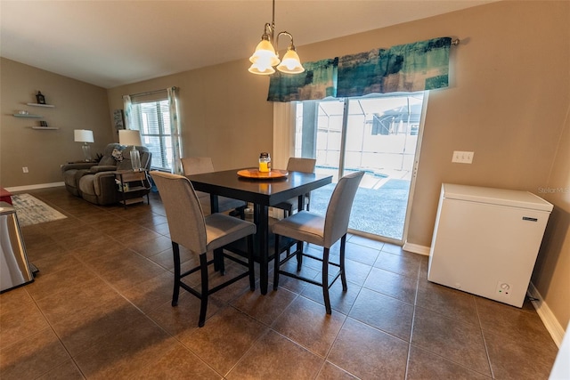 dining area featuring lofted ceiling, baseboards, and dark tile patterned flooring