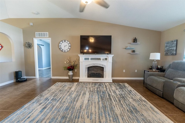 living area featuring tile patterned floors, visible vents, a premium fireplace, ceiling fan, and vaulted ceiling