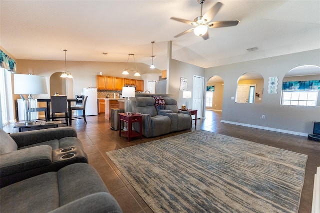 living room featuring a wealth of natural light, vaulted ceiling, arched walkways, and dark tile patterned flooring