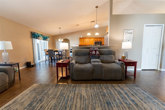 living area with lofted ceiling, dark tile patterned flooring, baseboards, and arched walkways