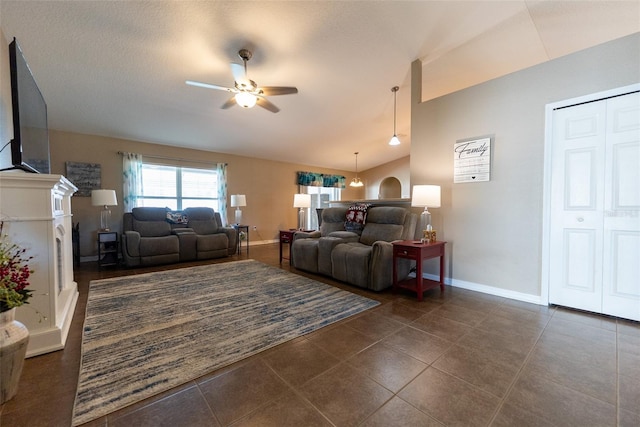 living room featuring baseboards, dark tile patterned flooring, a ceiling fan, and vaulted ceiling