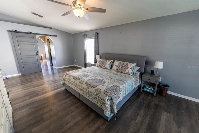 bedroom featuring dark wood-style floors, visible vents, baseboards, arched walkways, and a barn door