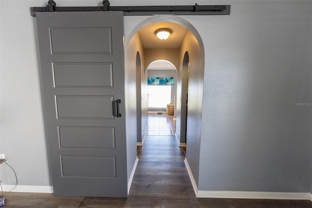 hallway with baseboards, arched walkways, and dark wood-style flooring