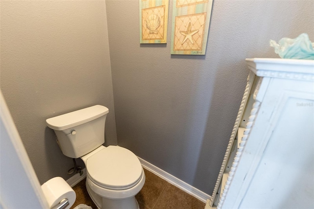 bathroom with tile patterned flooring, toilet, a textured wall, and baseboards