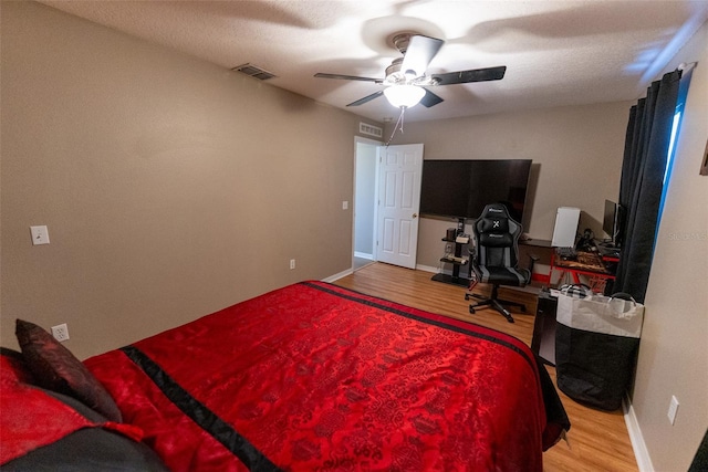 bedroom featuring visible vents, ceiling fan, baseboards, and wood finished floors