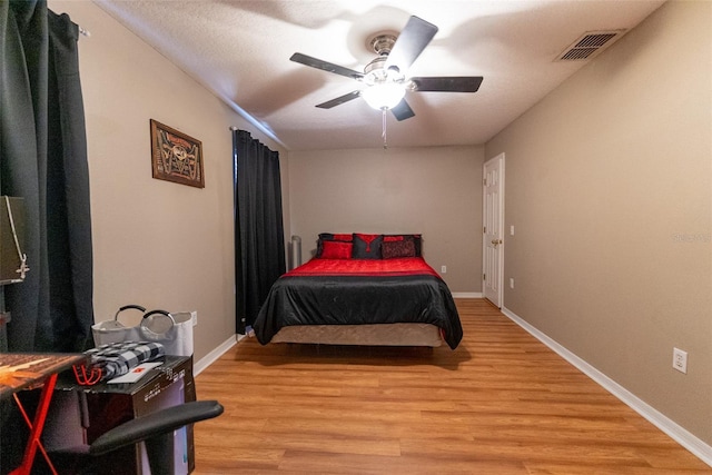 bedroom featuring visible vents, baseboards, ceiling fan, and light wood finished floors