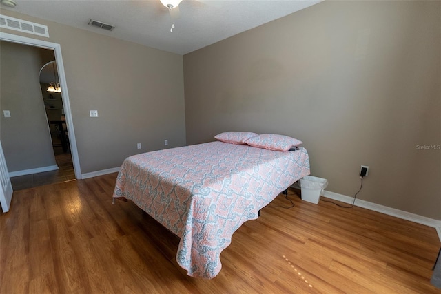 bedroom with visible vents, baseboards, and wood finished floors