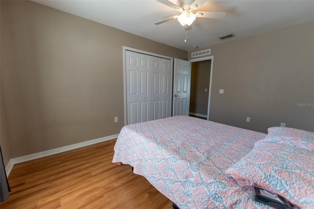 bedroom with light wood-style flooring, baseboards, visible vents, and a closet