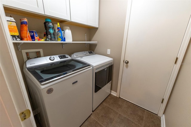 laundry area featuring washer and dryer, cabinet space, and dark tile patterned floors