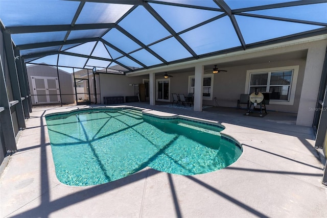 outdoor pool with glass enclosure, a patio, an outdoor structure, a storage unit, and a ceiling fan