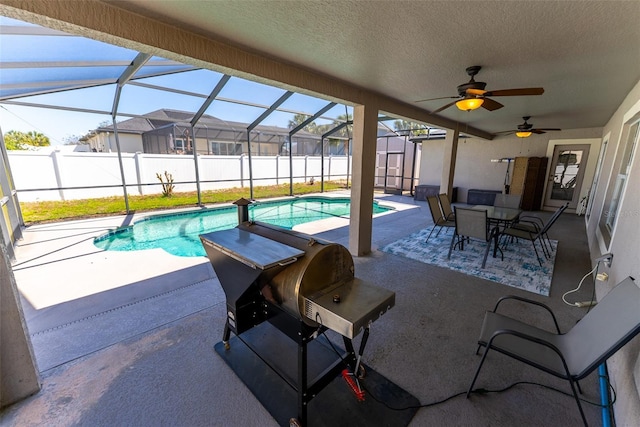 view of pool with a ceiling fan, glass enclosure, a grill, a fenced in pool, and a patio area