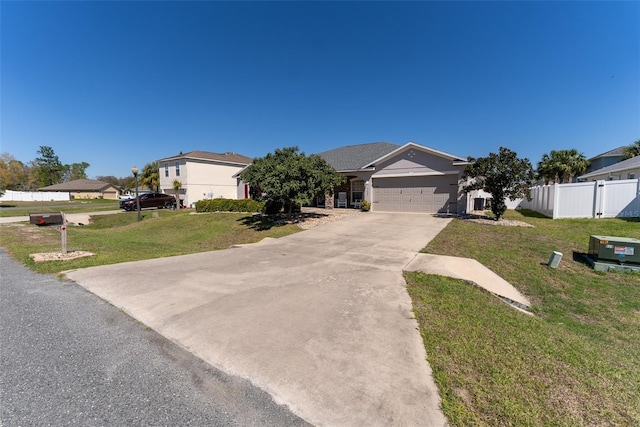 view of front of home featuring driveway, an attached garage, a front lawn, and fence