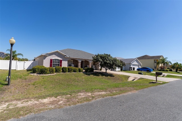 ranch-style house featuring a front lawn, fence, concrete driveway, stucco siding, and a gate