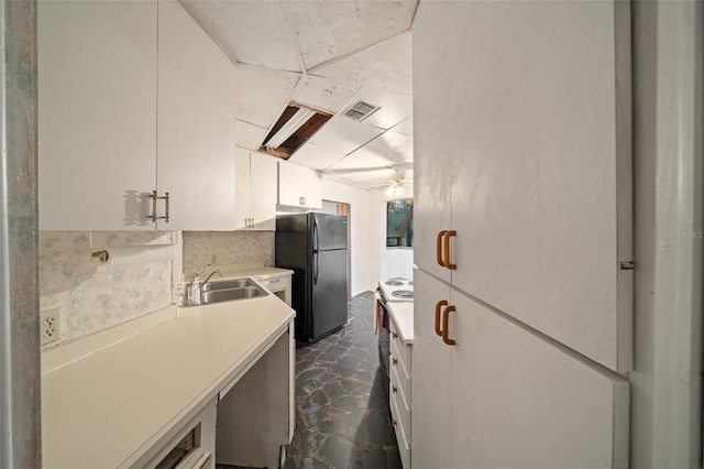 kitchen with visible vents, light countertops, freestanding refrigerator, white cabinets, and a sink