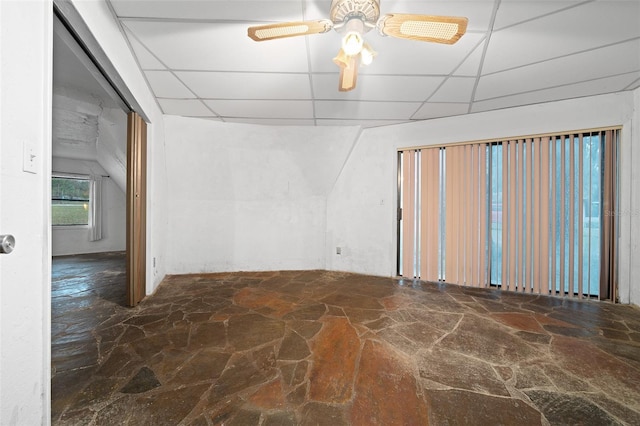 empty room featuring a paneled ceiling, ceiling fan, and stone flooring